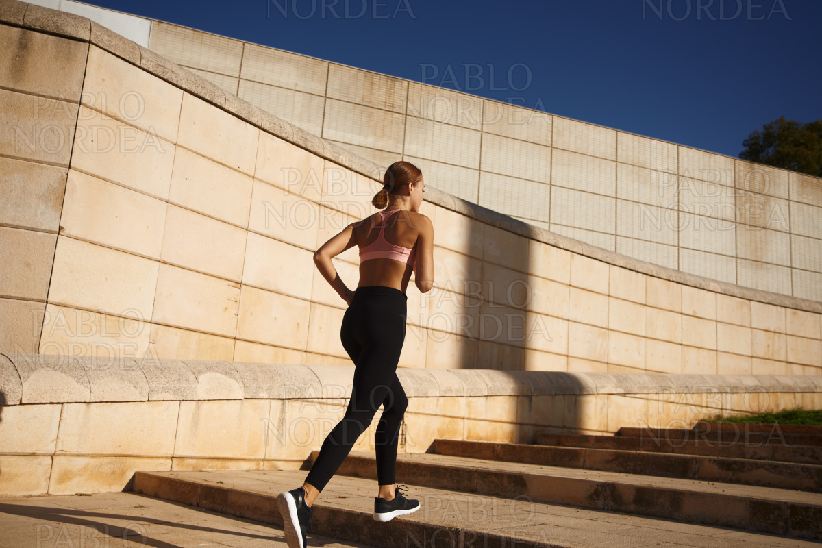 Beautiful fit woman running up stairs stock photo
