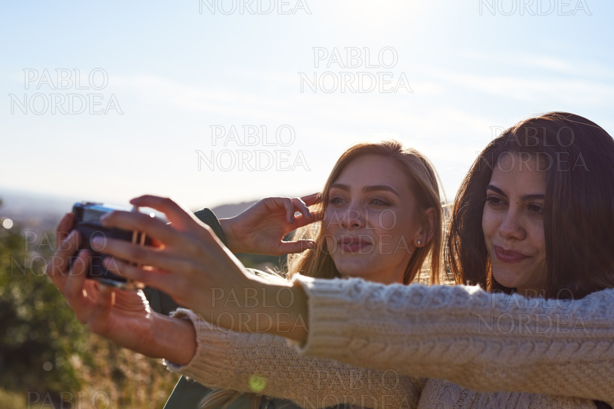 Female friends enjoying selfie on sunny day stock photo
