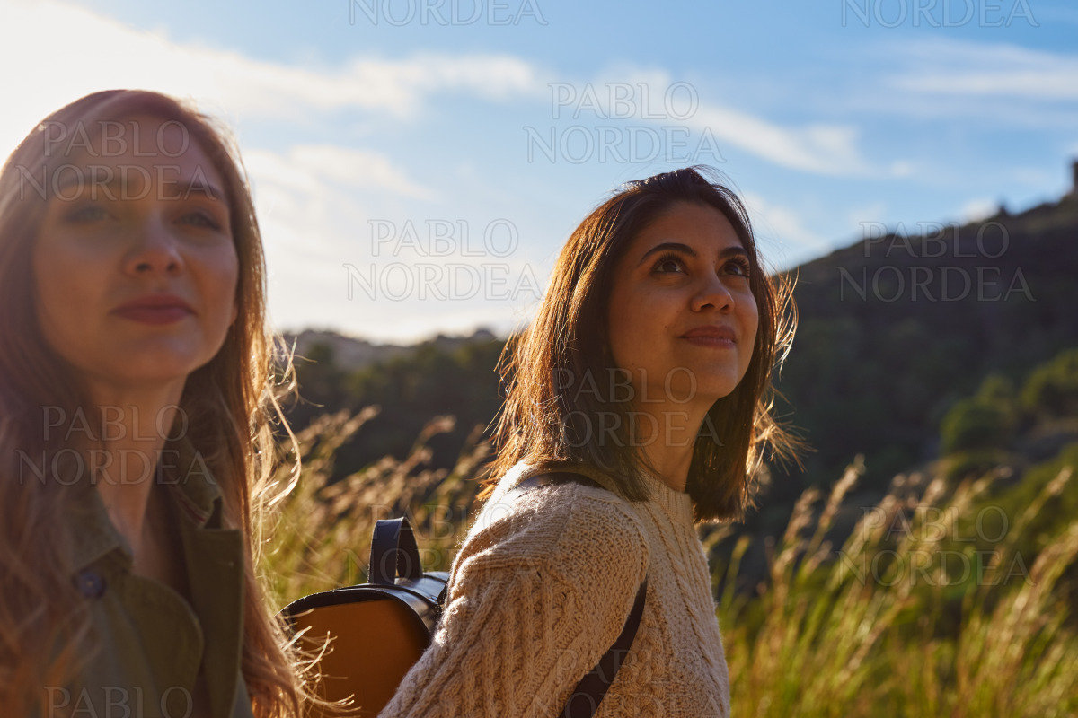 Female friends standing on mountain looking away stock photo