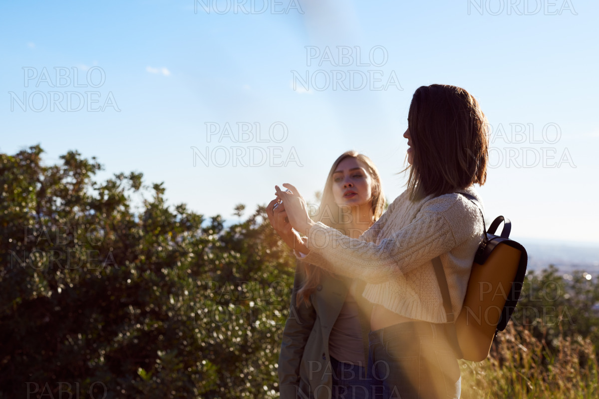 Female friends standing with camera in mountains stock photo