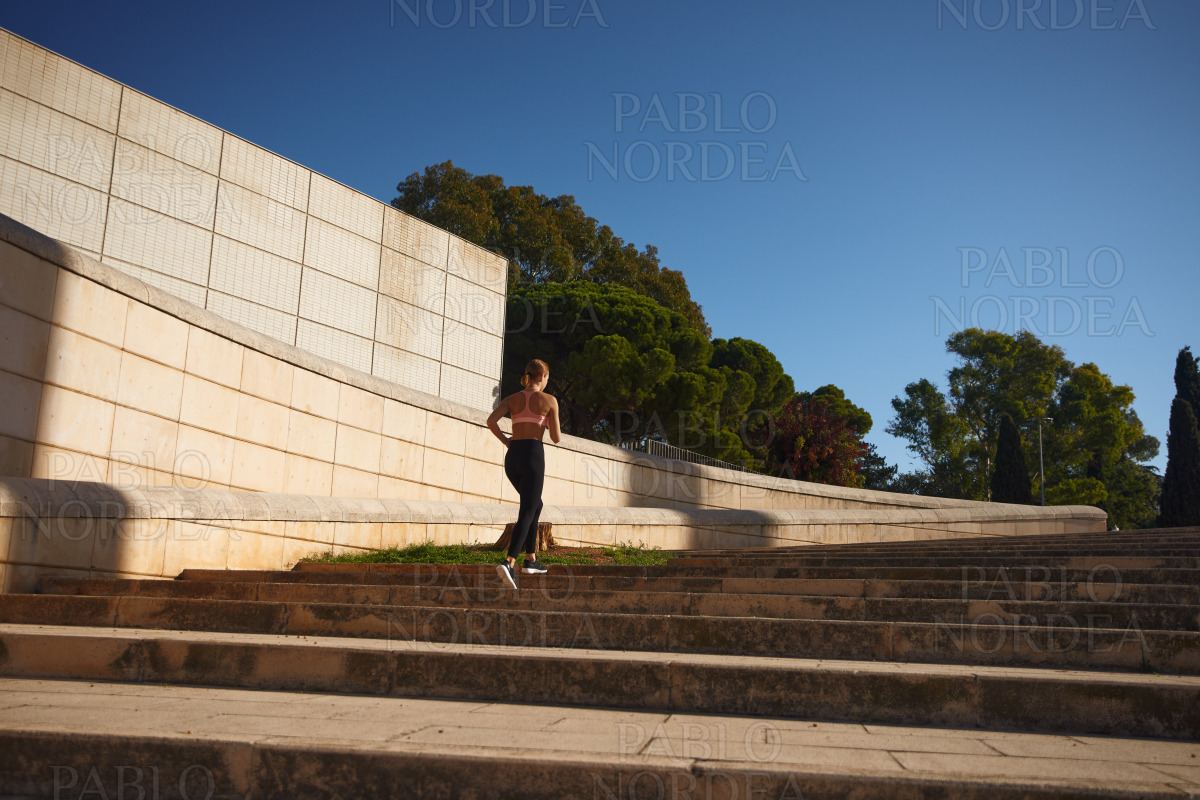 Fit woman practising jogging in sun stock photo