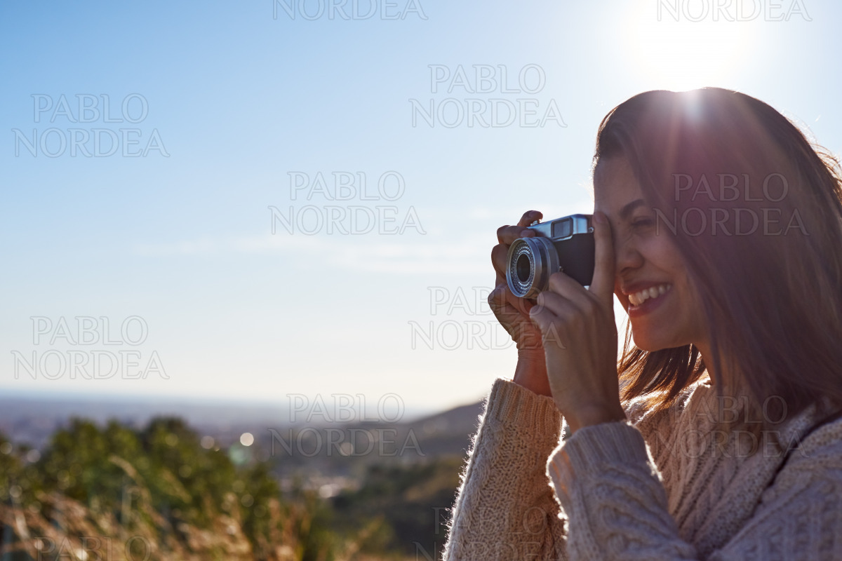 Happy woman photographing in mountains in sun stock photo