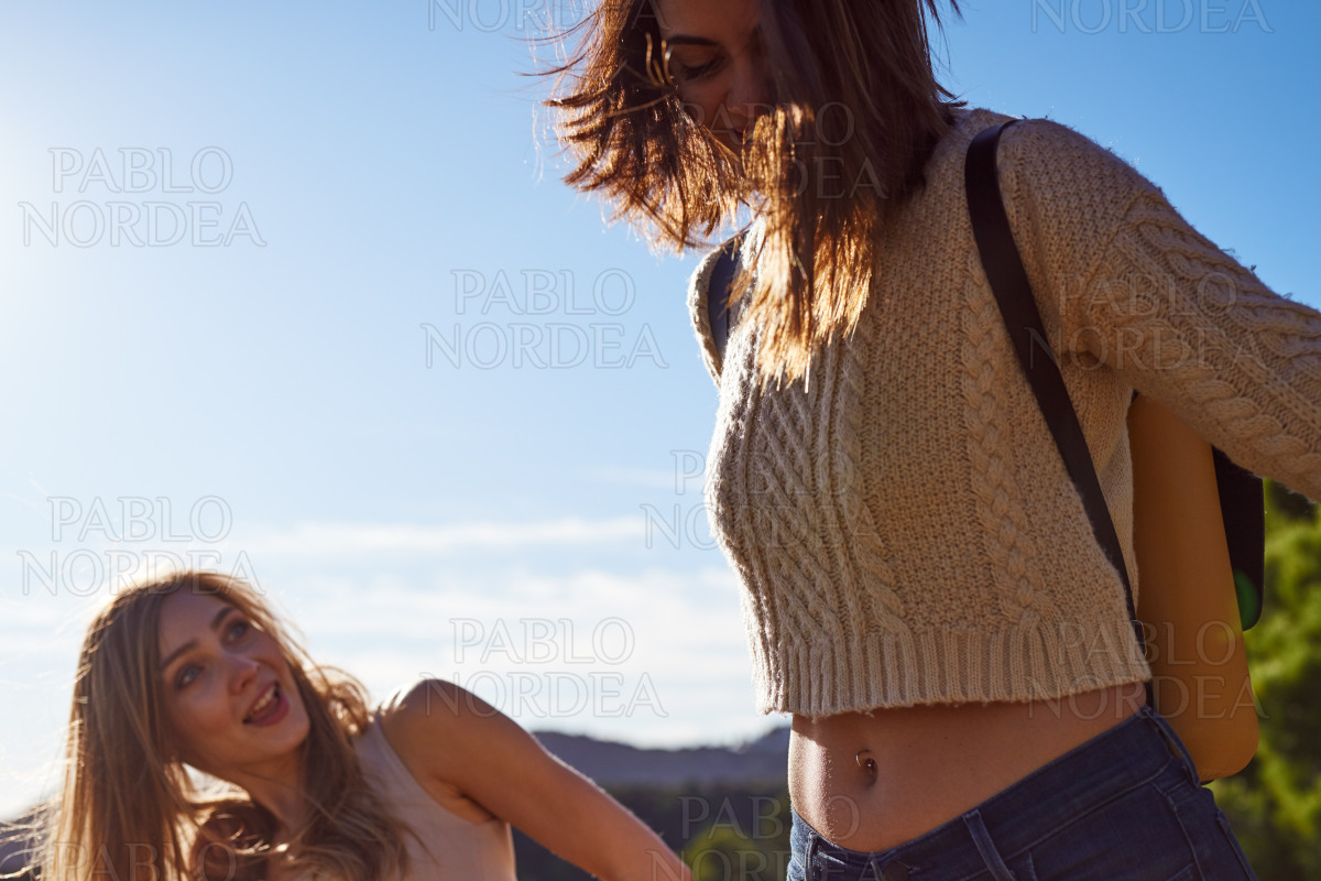 Playful female friends walking together outdoors stock photo