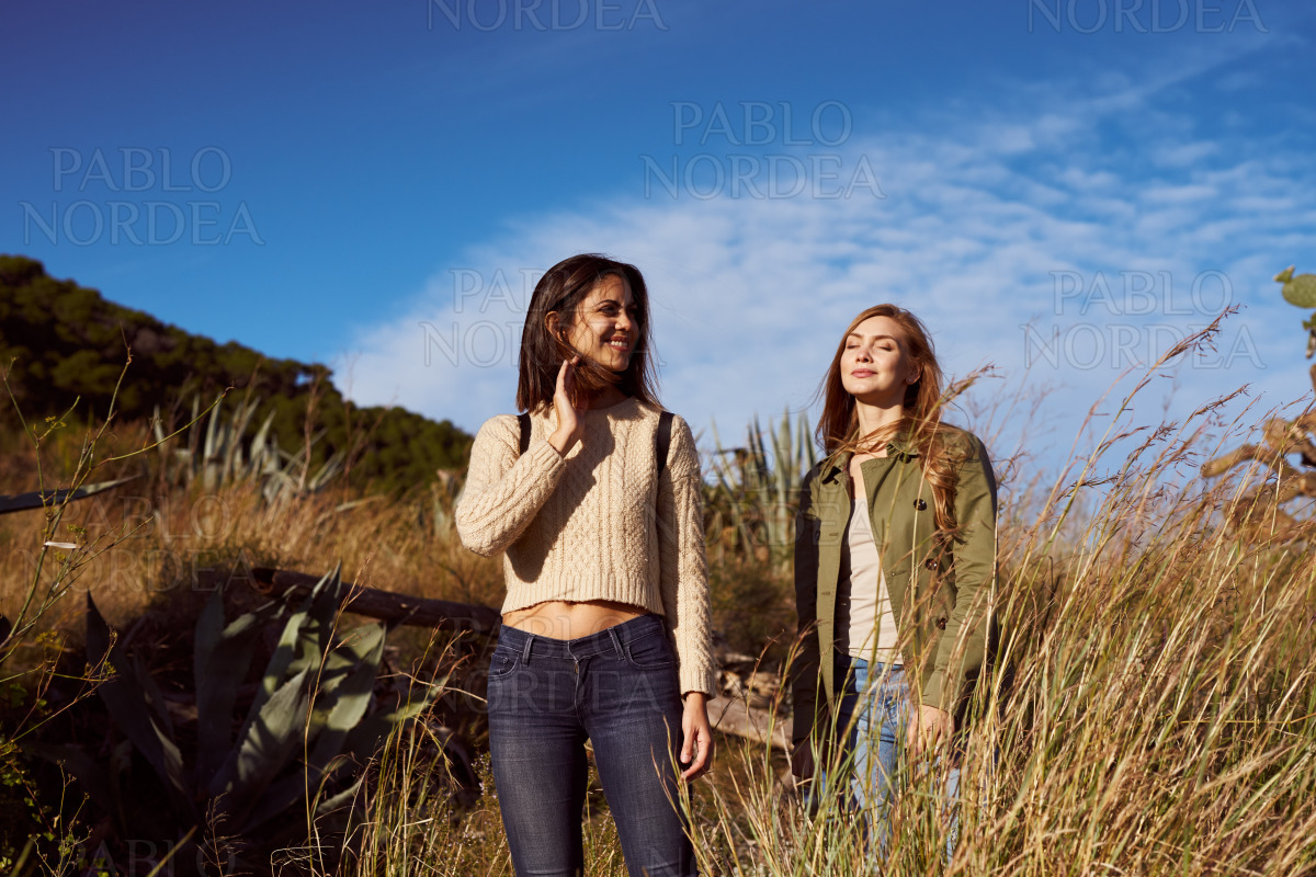 Smiling friends standing in grass in mountains stock photo