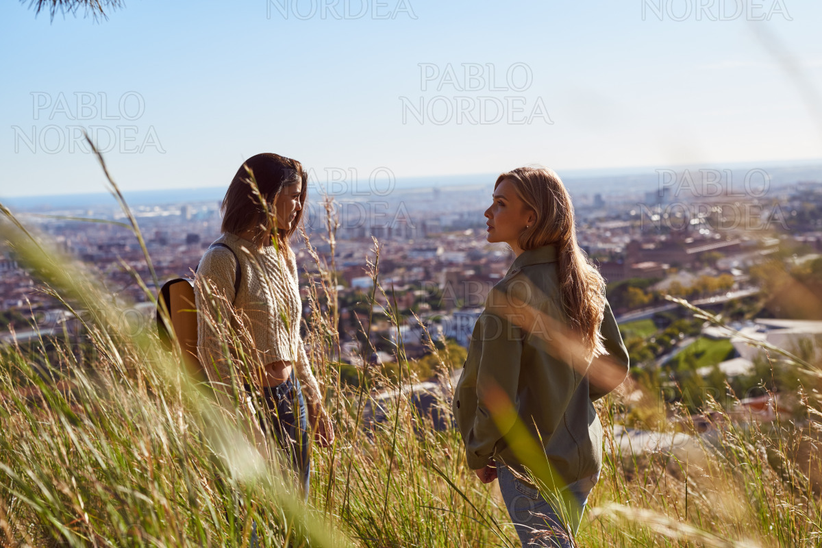 Two female friends having a chat on a hilltop stock photo