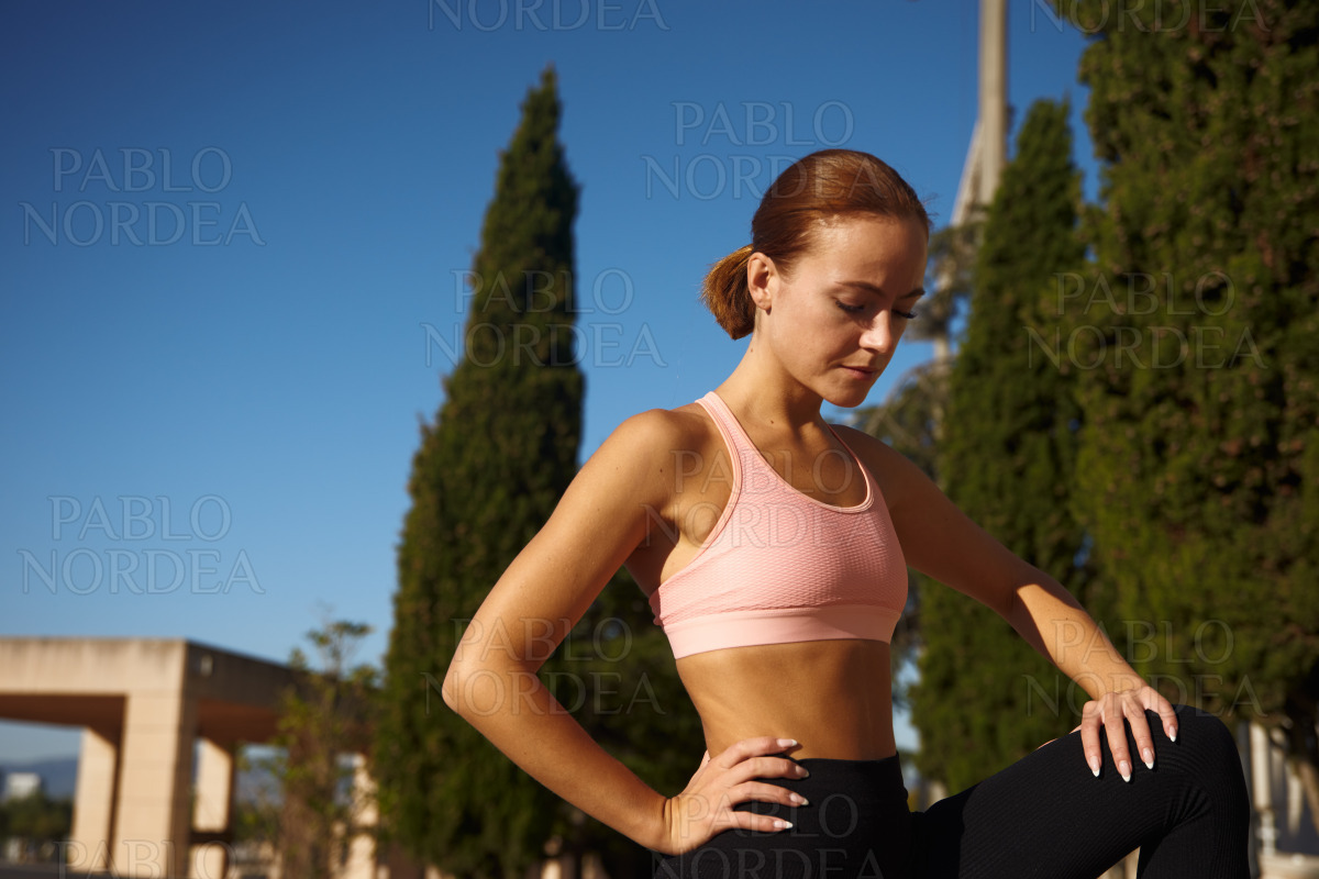 Woman stretching in park with hand on knee stock photo