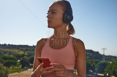 Blond woman listening to music in park