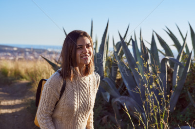 Elated young lady walking along some aloe