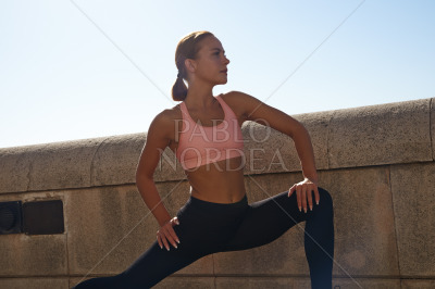 Fit woman standing and stretching on pavement
