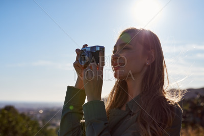Happy woman photographing mountains in sun
