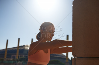 Portrait of woman stretching against column