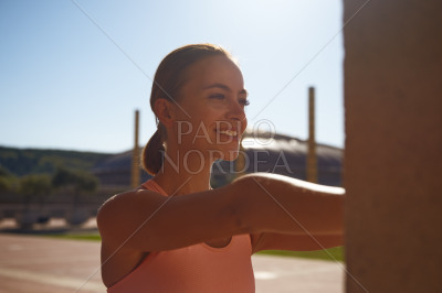 Smiling woman stretching in park on sunny day