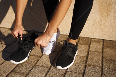 Sporty woman tying shoes on street