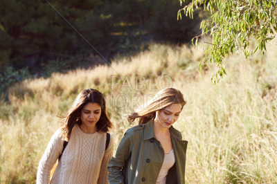 Two female friends walking together in the woods