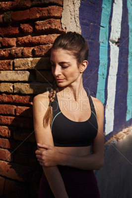 Woman leans against a wall in the sun