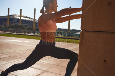 Woman standing against column while stretching
