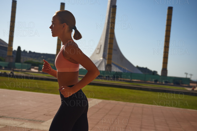 Beautiful woman jogging on street in sun