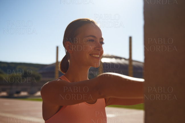 Smiling woman stretching in park on sunny day stock photo