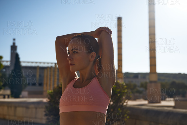 Sporty woman stretching against blue sky