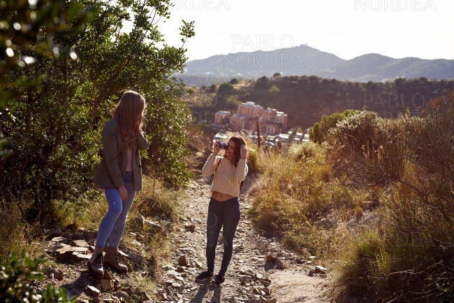 Two female friends standing and photographing