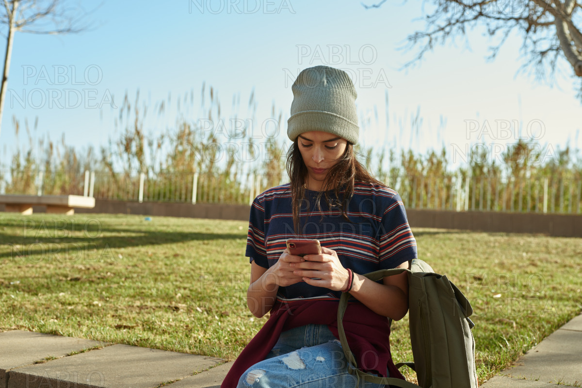 Attractive young woman using cellphone outdoors stock photo