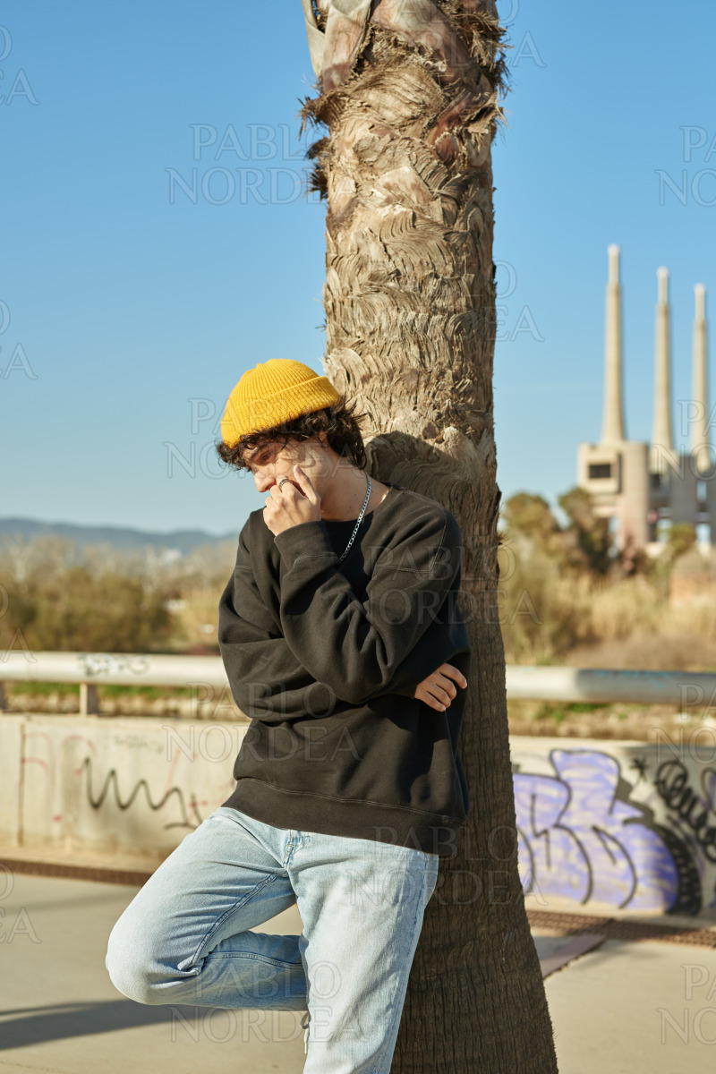 Contemplative young man leaning against a tree stock photo
