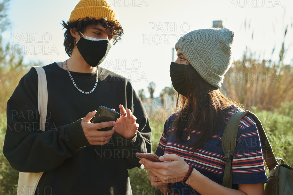 Couple chatting while holding cellphones outdoors stock photo