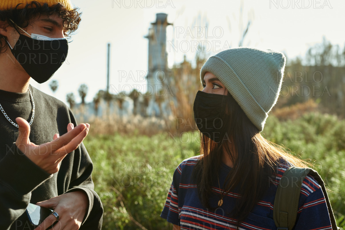 Couple in masks having a chat outdoors stock photo