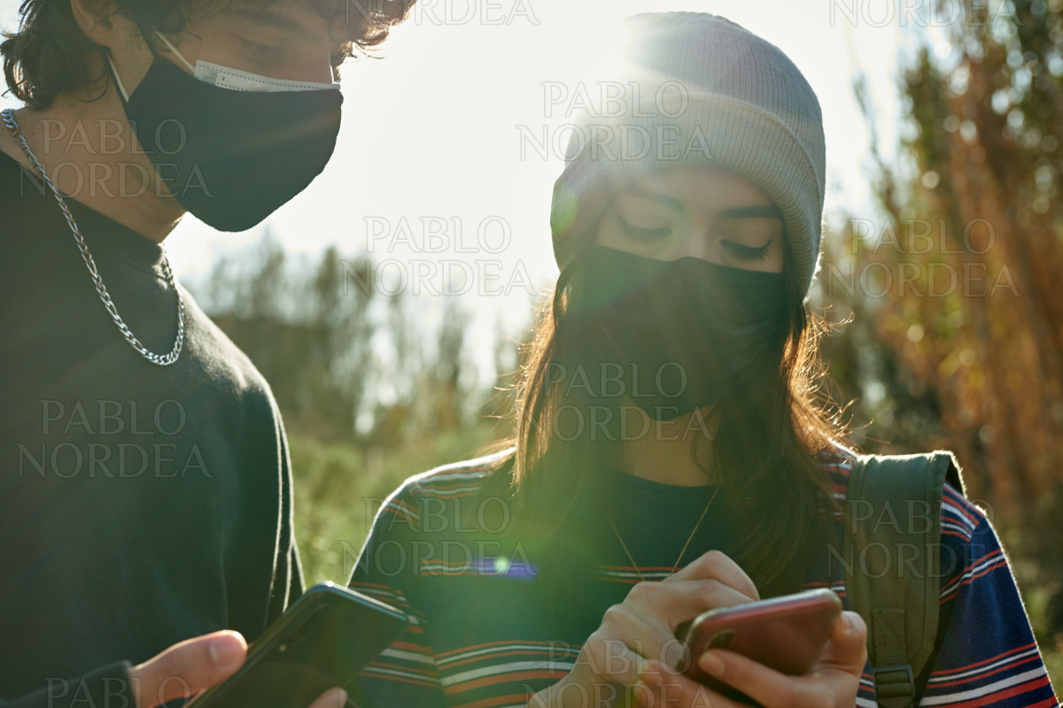 Cute young couple using cellphones outdoors stock photo