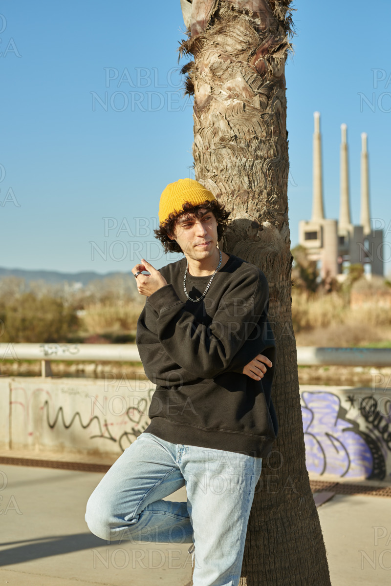 Intrigued young man leaning against a tree stock photo