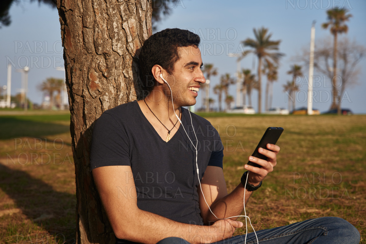 Smiing young man holds a cell phone stock photo
