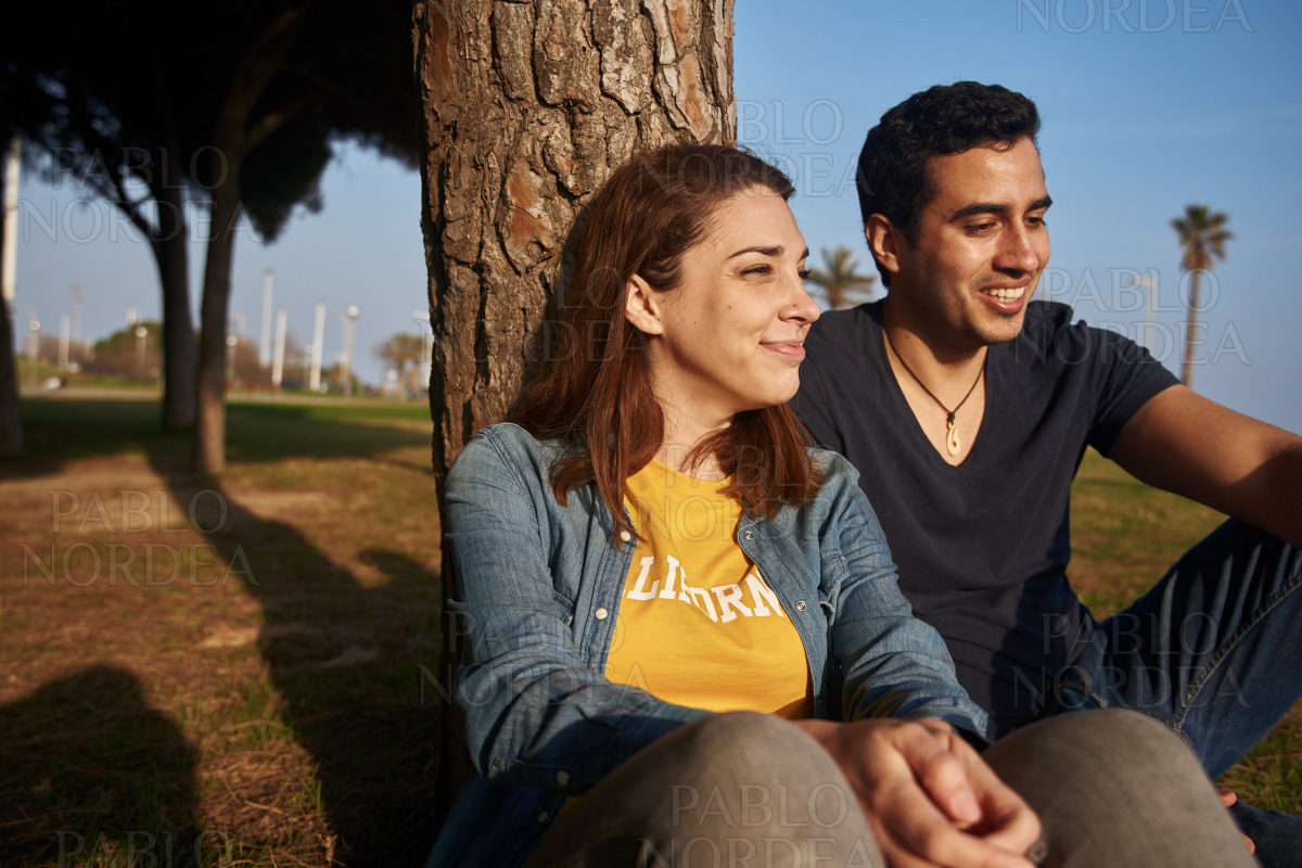 Smiling attrative young couple seated in the park stock photo