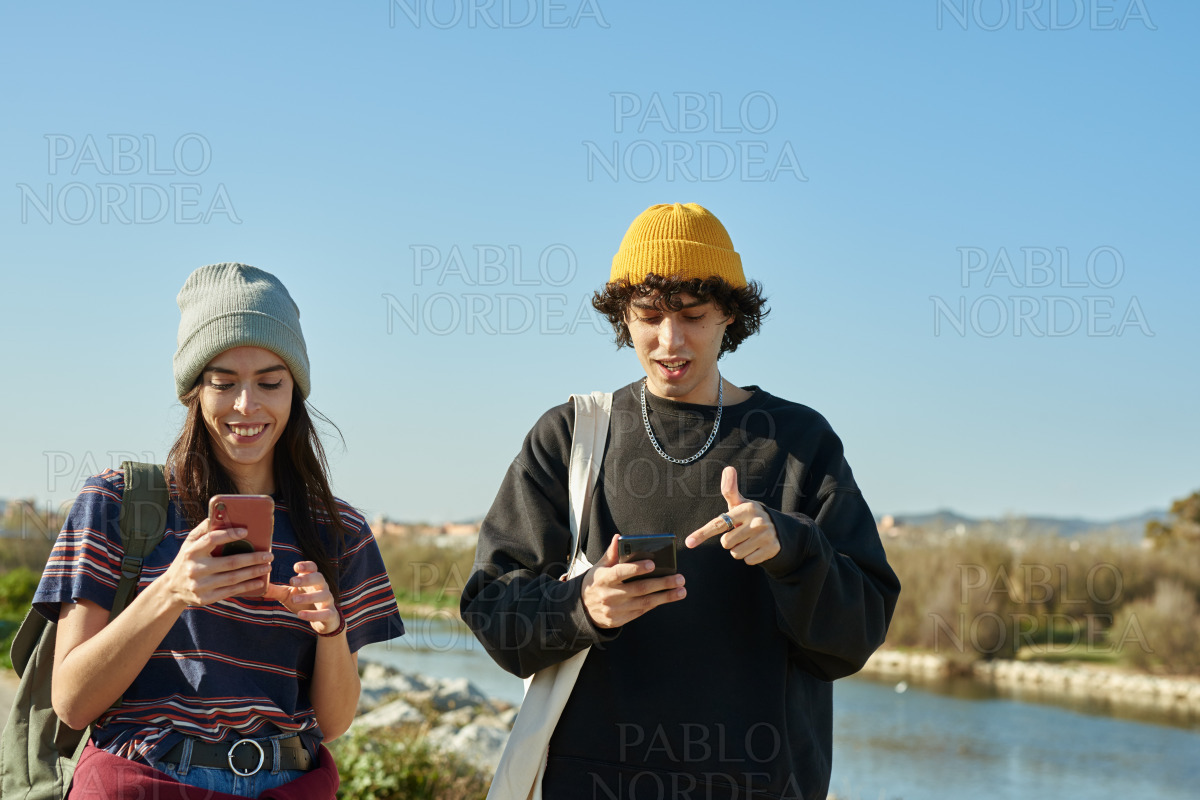 Two busy young people texting and walking stock photo