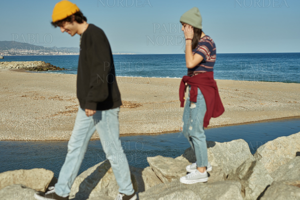 Two engaged young people walking on rocks stock photo