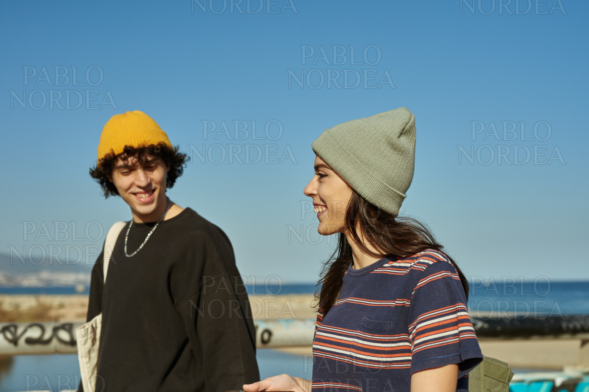 Two jaunty young people strolling along the beach stock photo
