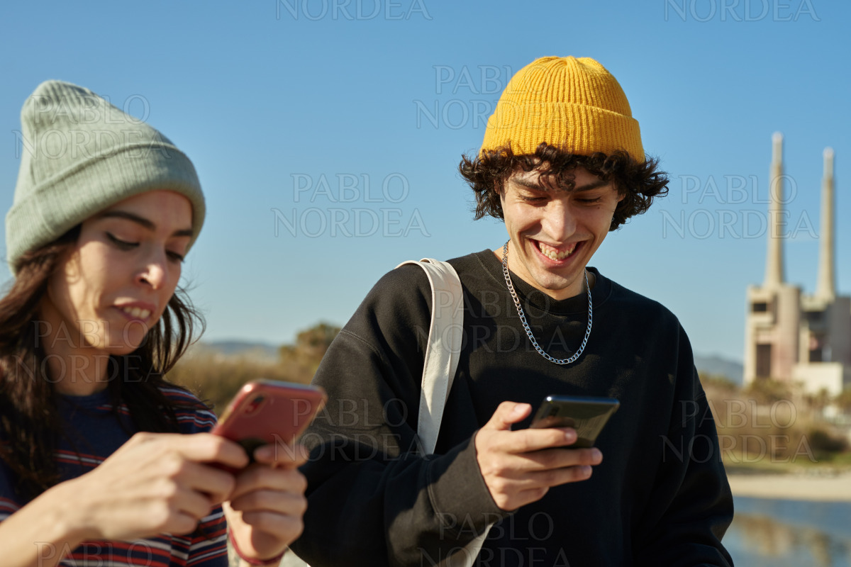 Two jolly young people engaged with their phones stock photo
