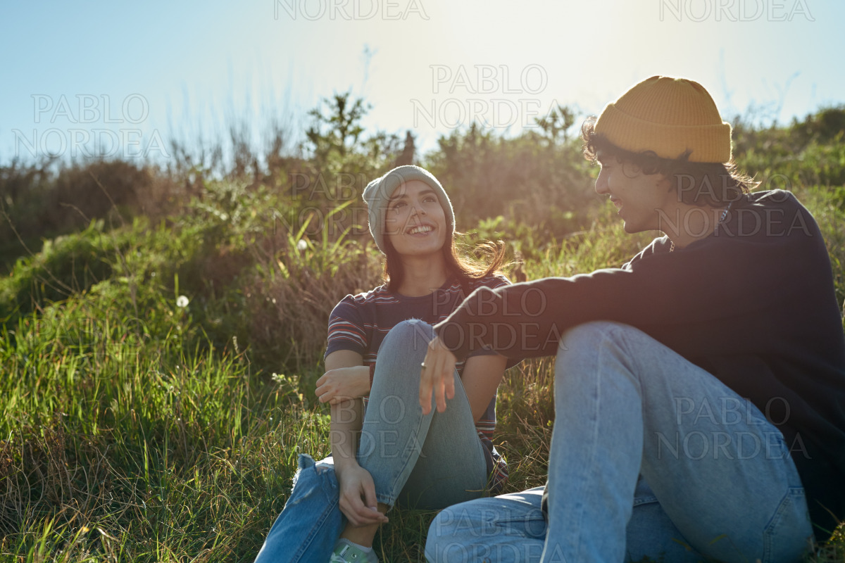 Two radiant young people sitting on a hill stock photo