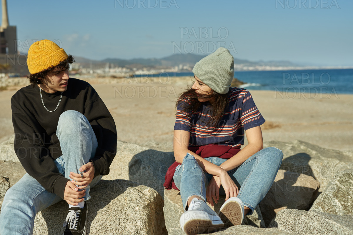 Two riveted young people sitting on rocks stock photo
