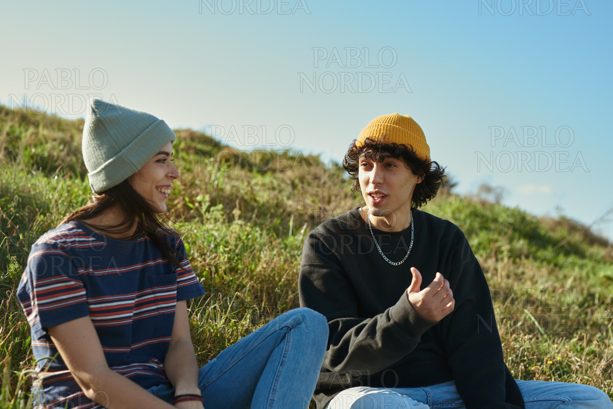 Two vibrant young people sitting on a hill stock photo