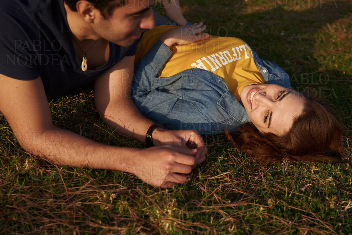 Woman smiles at the man as they lay on the grass stock photo