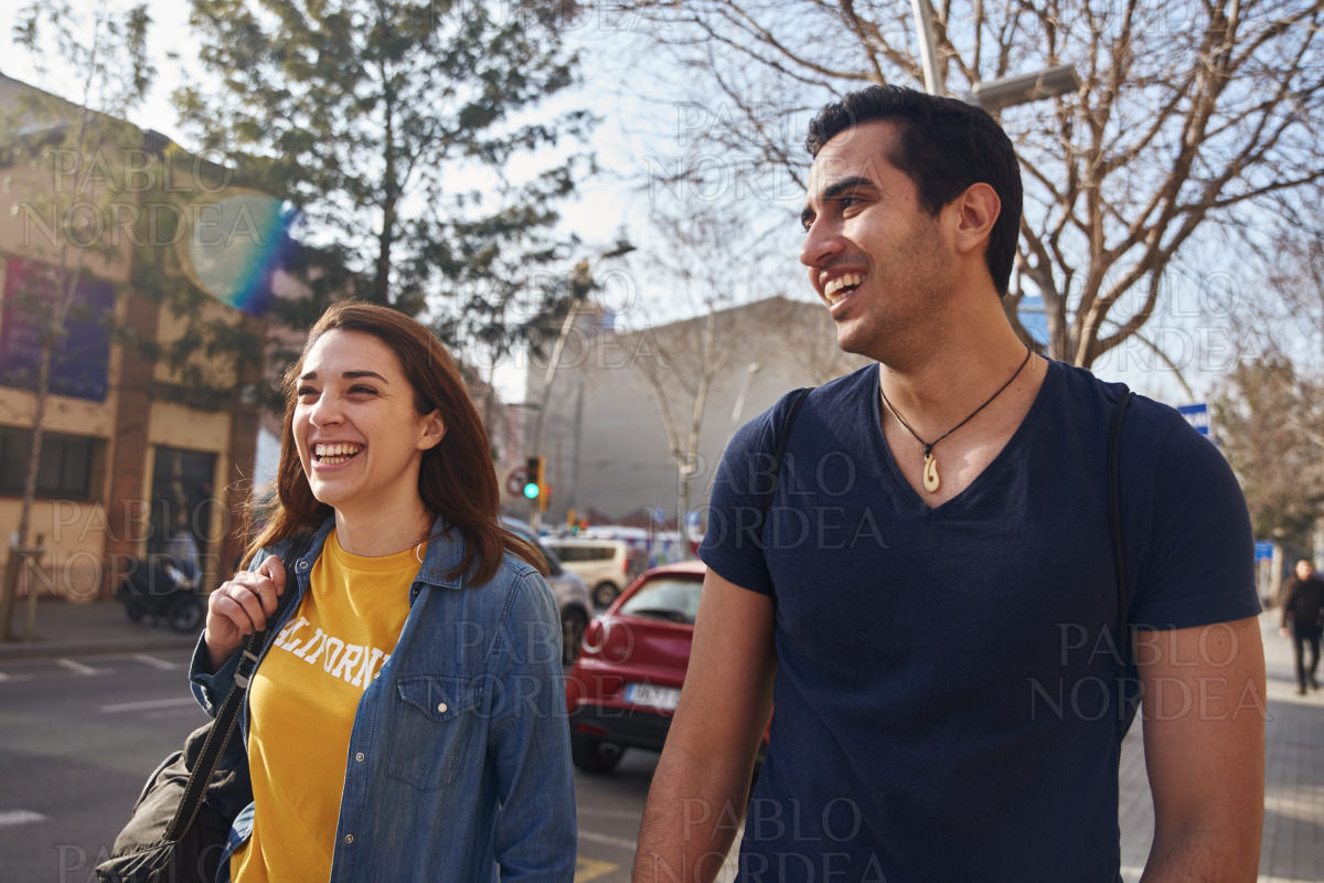 Young couple laughing as they walk stock photo