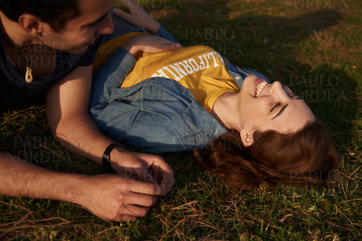 Young couple laughing together outdoors in park stock photo