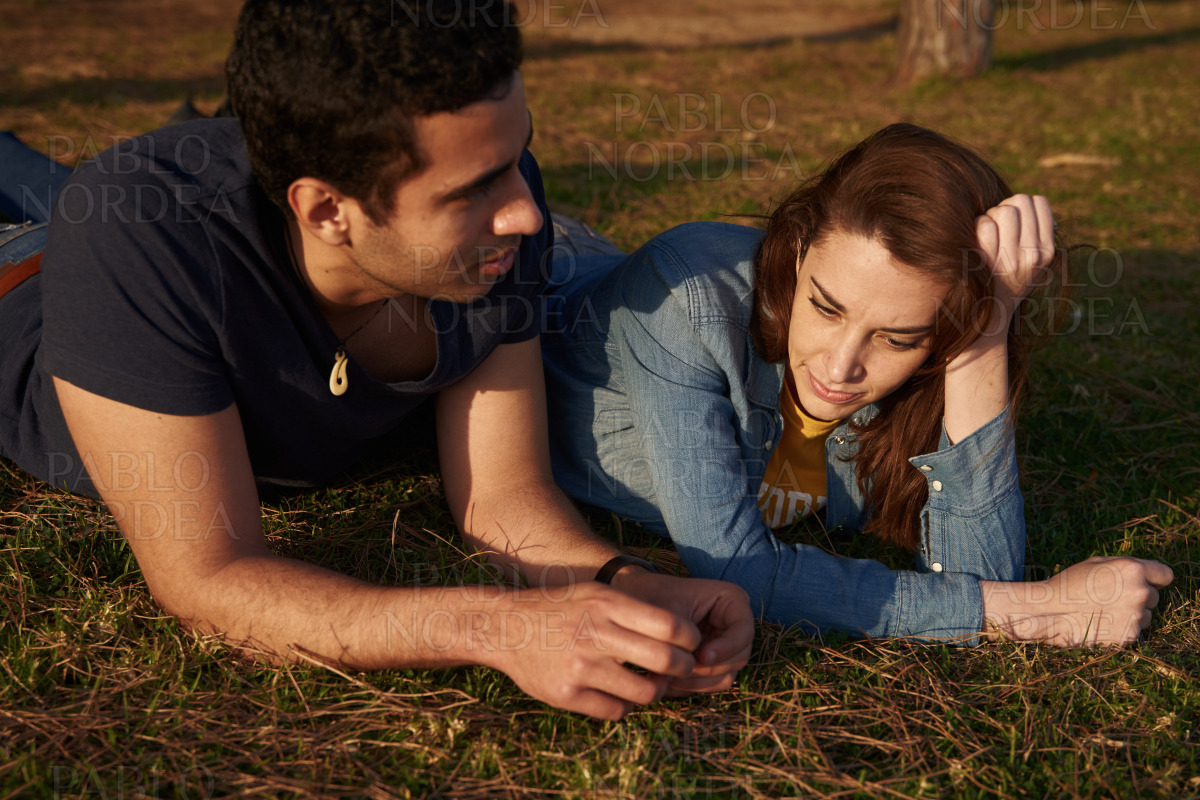 Young couple lying on the grass near trees stock photo
