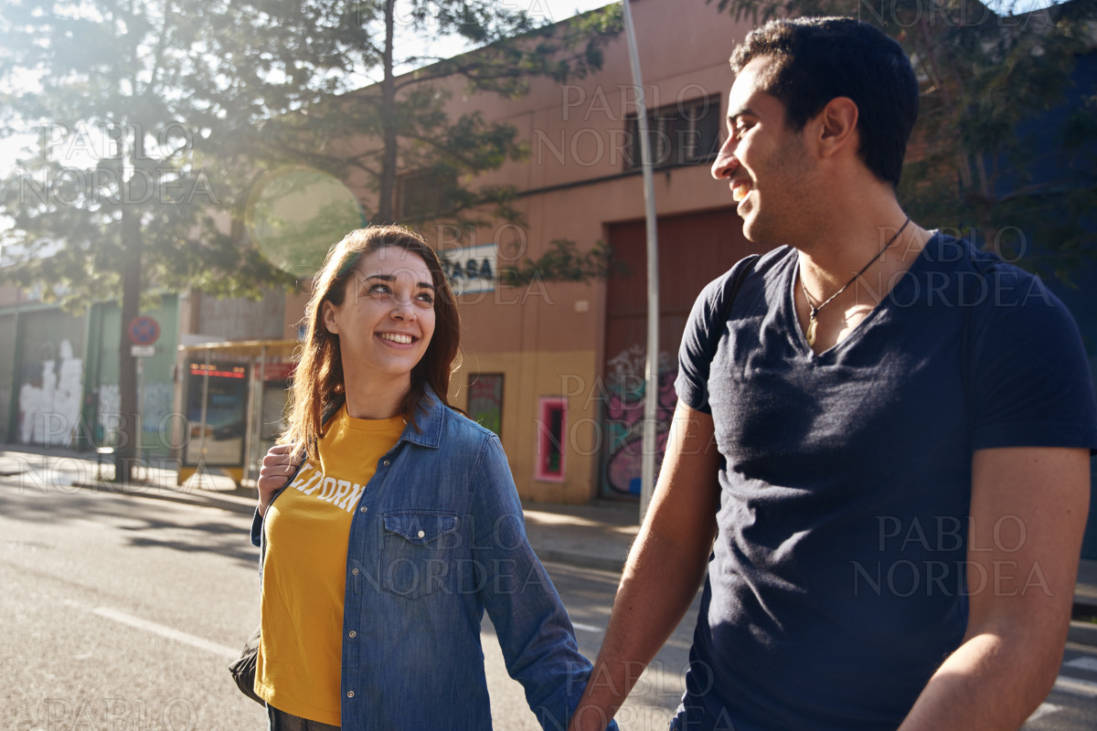 Young smiling couple holding hands as they walk stock photo