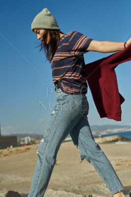 A breezy young lady walking on rocks along a beach