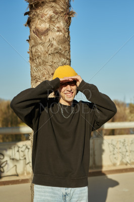 A gleeful young man standing against a tree