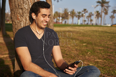 Man smiles down at his phone in the park