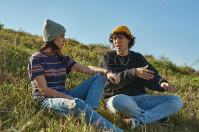 Two diverted young people having a chat on a hill