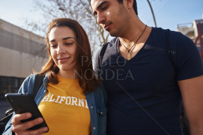Young couple looking at a cell phone outdoors