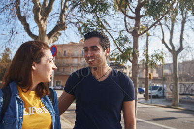 Young couple smile at each other as they walk